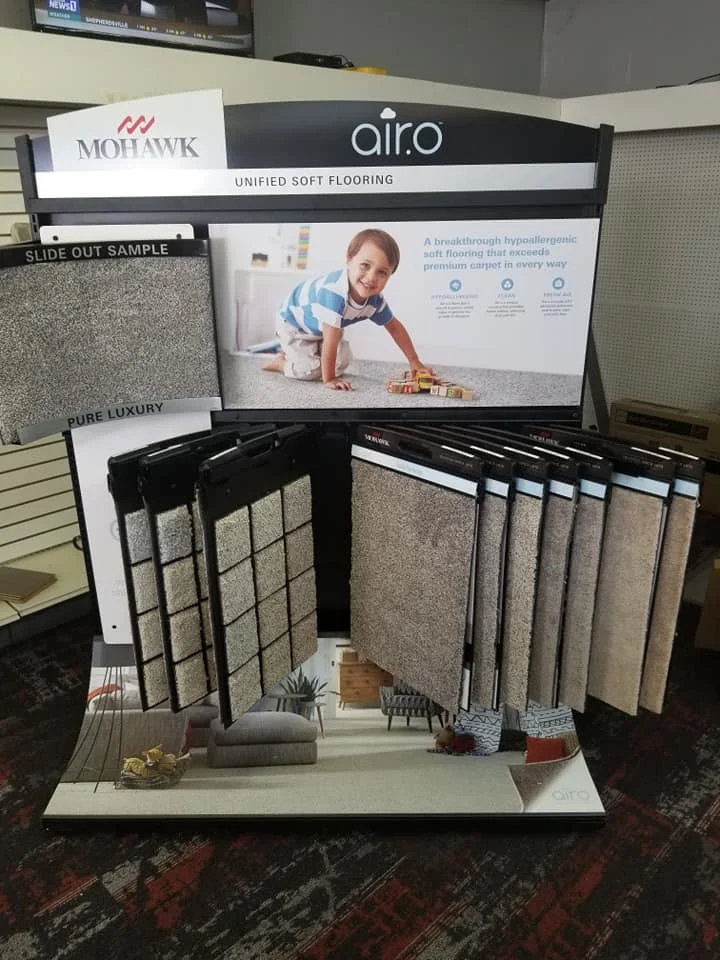 A carpet sample display for Mohawk Air.o unified soft flooring, featuring various carpet swatches and an image of a child playing on the floor.