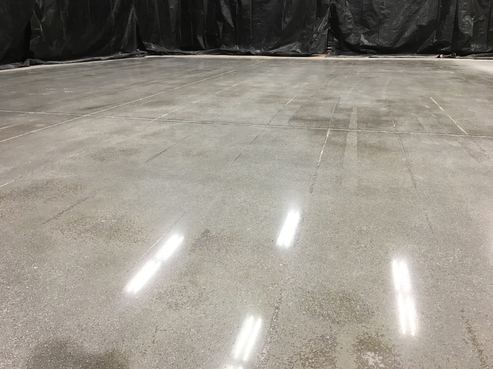 Polished concrete floor with visible light reflections and black plastic sheets covering the surrounding walls.